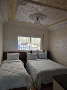 a bedroom with two beds and a window at NOUARA Appart'hotel in Chefchaouen