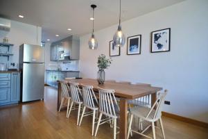 a kitchen with a wooden table and chairs and a refrigerator at Hommie Home Pattaya in Ban Krathing Lai