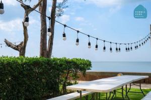 a picnic table in front of the ocean with lights at Hommie Home Pattaya in Ban Krathing Lai