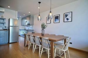 a kitchen with a wooden table and chairs and a refrigerator at Hommie Home Pattaya in Ban Krathing Lai