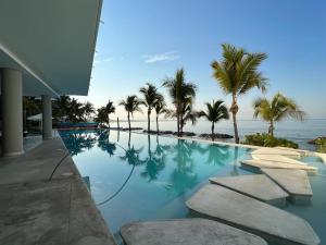 ein Swimmingpool mit Palmen und dem Meer in der Unterkunft Park Life Narval in Bucerías
