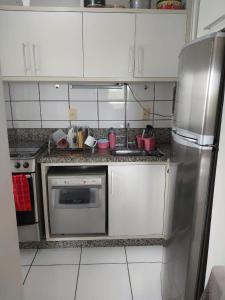 a kitchen with white cabinets and a stainless steel refrigerator at Apartamento 2 quartos Centro de Araranguá in Araranguá +3 photos