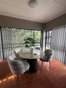 a dining room with a table and chairs and a plant at TinasRose in Uvongo Beach