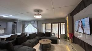 a living room with a couch and a tv at TinasRose in Uvongo Beach +6 photos