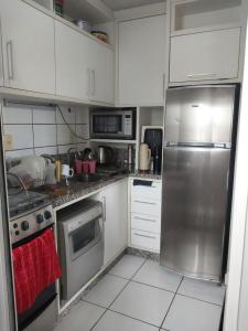 a kitchen with white cabinets and a stainless steel refrigerator at Apartamento 2 quartos Centro de Araranguá in Araranguá