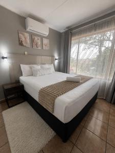 a bedroom with a large bed and a window at TinasRose in Uvongo Beach