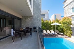 a patio with a table and chairs and a swimming pool at Ixia Pool Villa with sea view roof top in Ixia