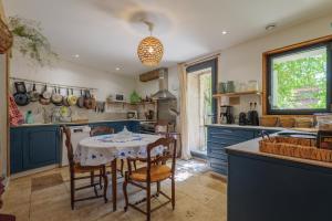 a kitchen with blue cabinets and a table with chairs at Chambres D’hôtes - Les Agrions in Saint-Remèze +51 photos