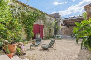 a courtyard with two chairs and a red door at Chambres D’hôtes - Les Agrions in Saint-Remèze