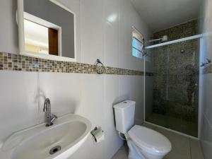 a bathroom with a sink and a toilet and a mirror at Pousada in Guarujá