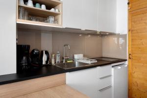 a kitchen with white cabinets and a sink at Studio Moderne Pied Des Pistes 4 p in La Pierre Saint Martin +14 photos