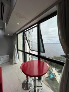 a red table in front of a large window at Tropical Executive Vista Pôr do Sol in Manaus
