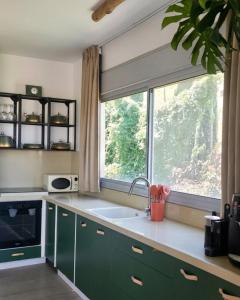 a kitchen with green cabinets and a large window at מרום הגילבוע in Gid‘ona