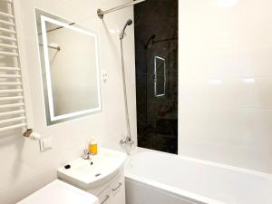 a white bathroom with a sink and a mirror at Apartament Gozo in Łódź +4 photos