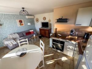 a kitchen and living room with a table and a couch at appartement avec piscine commune le chêne blc in Gargas