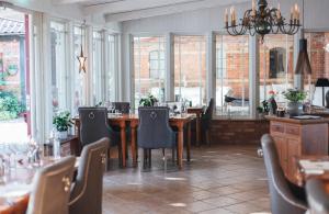 a dining room with tables and chairs and windows at Blåsingsborgs Gårdshotell på Österlen in Kivik
