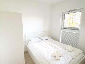 a white bedroom with two white pillows on a bed at Apartament Gozo in Łódź