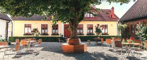 a courtyard with tables and chairs and a tree at Blåsingsborgs Gårdshotell på Österlen in Kivik