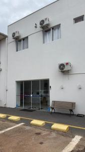 a white building with a bench in a parking lot at Hotel Iguaçu Chapecó in Chapecó