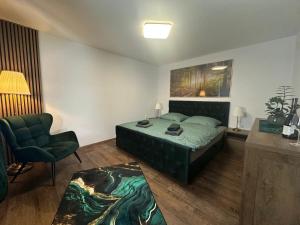 a bedroom with a green bed and a chair at Hauspark Residence in Žatec