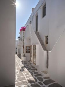 a narrow street with white buildings and flowers at Flair Naousa in Naousa
