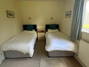 two twin beds in a room with a window at Lodge 22, Bodmin Holiday Park, Cornwall in Lanivet