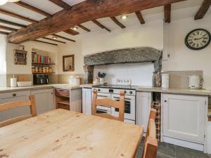 a kitchen with a wooden table and a clock on the wall at High Ickenthwaite Farmhouse in Ulverston