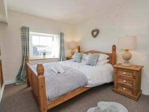 a bedroom with a large wooden bed and a window at High Ickenthwaite Farmhouse in Ulverston