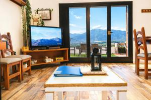 a living room with a tv and a table at Ca la Nena Morena - Casa con piscina privada, jardín y vistas al Montseny in Vallgorguina