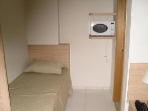 - une petite chambre avec un lit et un four micro-ondes dans l'établissement Apartamento Golden Dolphin Express, à Caldas Novas