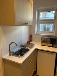 a small kitchen with a sink and a window at Sunny Garden WFH Retreat with Private Entrance and Parking near NEC BHX JLR in Solihull