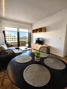 a living room with a table with chairs and a couch at Claudia Luxury Apartment near the beach with a pool, gym, and secure gated parking in Arenales del Sol