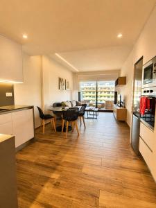 a kitchen and living room with a table and chairs at Claudia Luxury Apartment near the beach with a pool, gym, and secure gated parking in Arenales del Sol