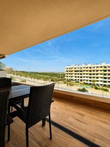 a balcony with a table and chairs and a large window at Claudia Luxury Apartment near the beach with a pool, gym, and secure gated parking in Arenales del Sol