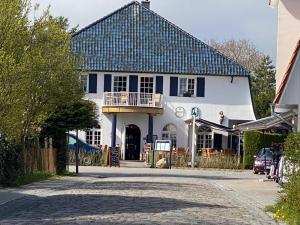 a white house with a blue roof and a balcony at Am Horizont 1 lichtdurchflutet modern zentral und ruhig Nähe Strand WLAN und Parkplatz inklusiv in Zingst