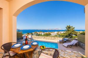 a table and chairs with a view of a swimming pool at Ariadne Villa in Plaka