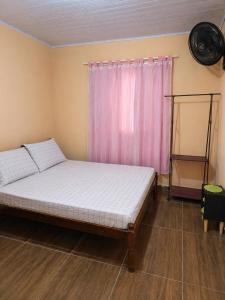 a bedroom with a bed and a pink curtain at Hospedagem Horizonte Azul- Recanto São Thomé in Eldorado