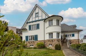 a large white house with blue shutters at Villa Vulkaneifel in Kelberg