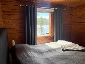 a bedroom with a bed in front of a window at Iken Mökit in Heinola