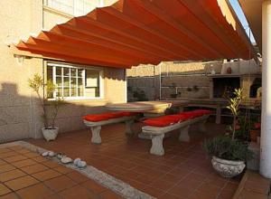 a patio with benches and a table and an umbrella at Casa Mar de Viladesuso in Oia