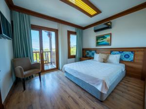 a bedroom with a bed and a chair and windows at Hotel Azmakhan in Akyaka +29 photos