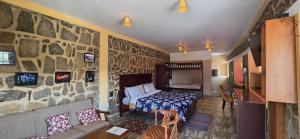 a bedroom with a bed and a stone wall at Cloudwalks Homestay in Kodaikānāl