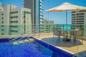 a table with an umbrella next to a swimming pool at Freitas Residence - Quinta Manuel Rodrigues in Recife