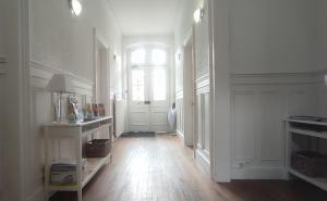 a white hallway with a window and a wooden floor at Au fil de Troyes in Sainte-Savine