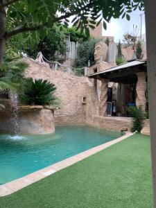 a swimming pool with green grass and a house at La Gata Negraa in Bácor