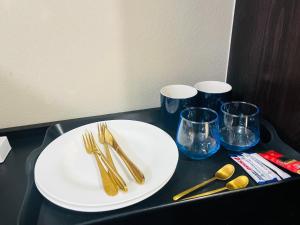 a table with a white plate and forks and glasses at Shiloh Tlokweng in Gaborone
