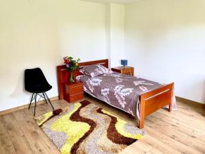 a bedroom with a bed and a chair and a rug at Przytulna Chata in Zamiany +1 photo