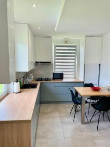 a kitchen with white cabinets and a table with chairs at Przytulna Chata in Zamiany
