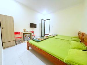 a bedroom with a large green bed and a desk at HAPPY TEA Motel in Long Hai