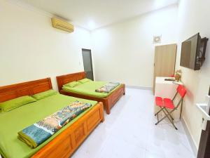 a bedroom with two beds and a television in it at HAPPY TEA Motel in Long Hai